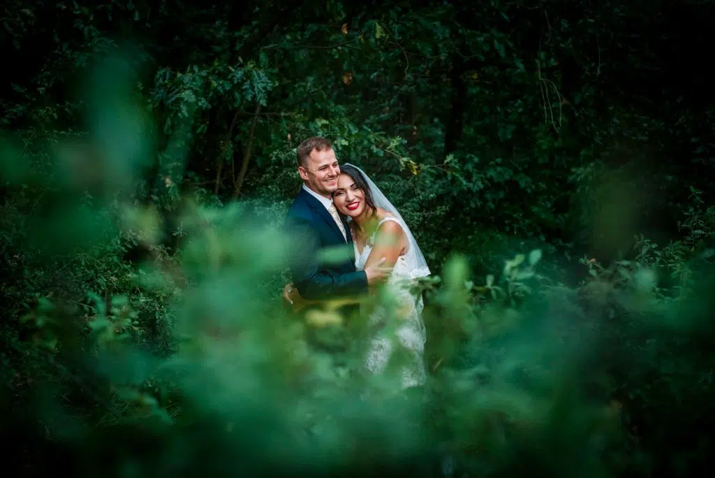 the bride is snuggling to the groom in the forest on their wedding portrait session