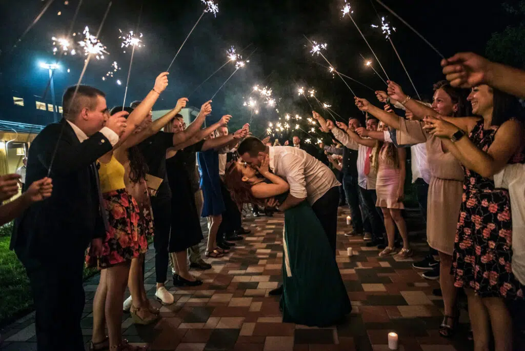 wedding portrait with sparklers and wedding guests sorrounding the couple